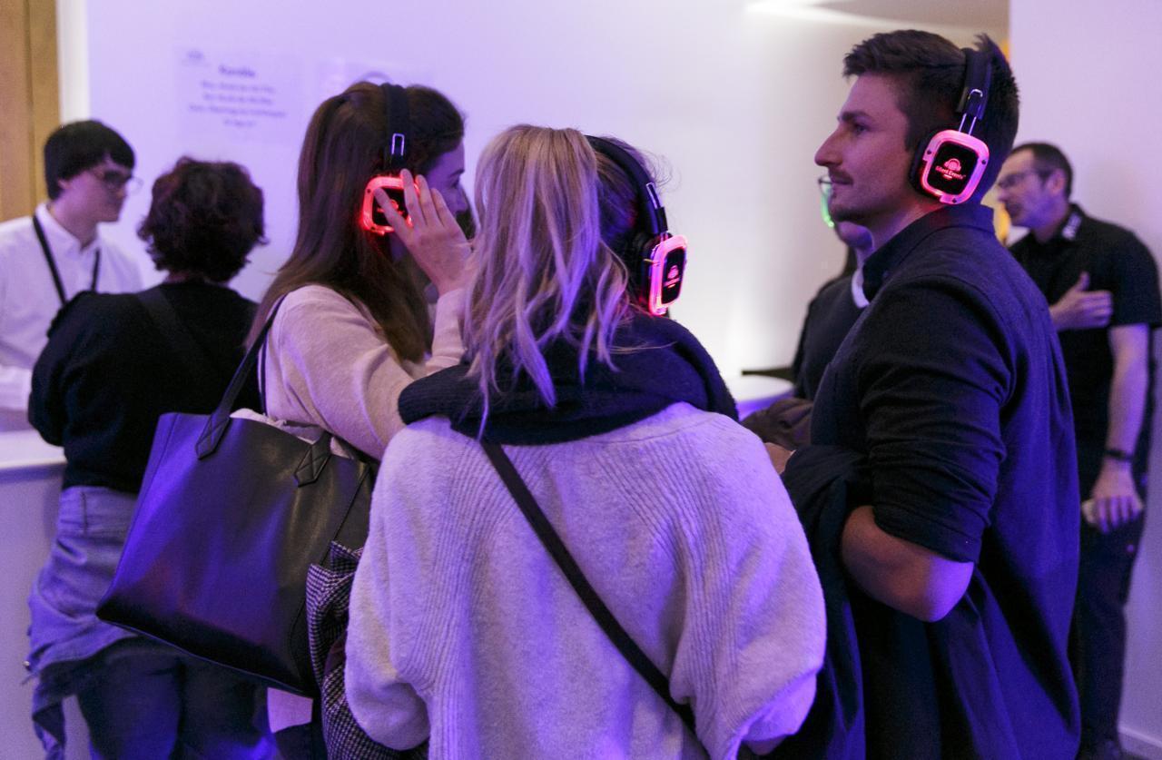 Drei Menschen mit Kopfhörern hören im Museum Musik.
